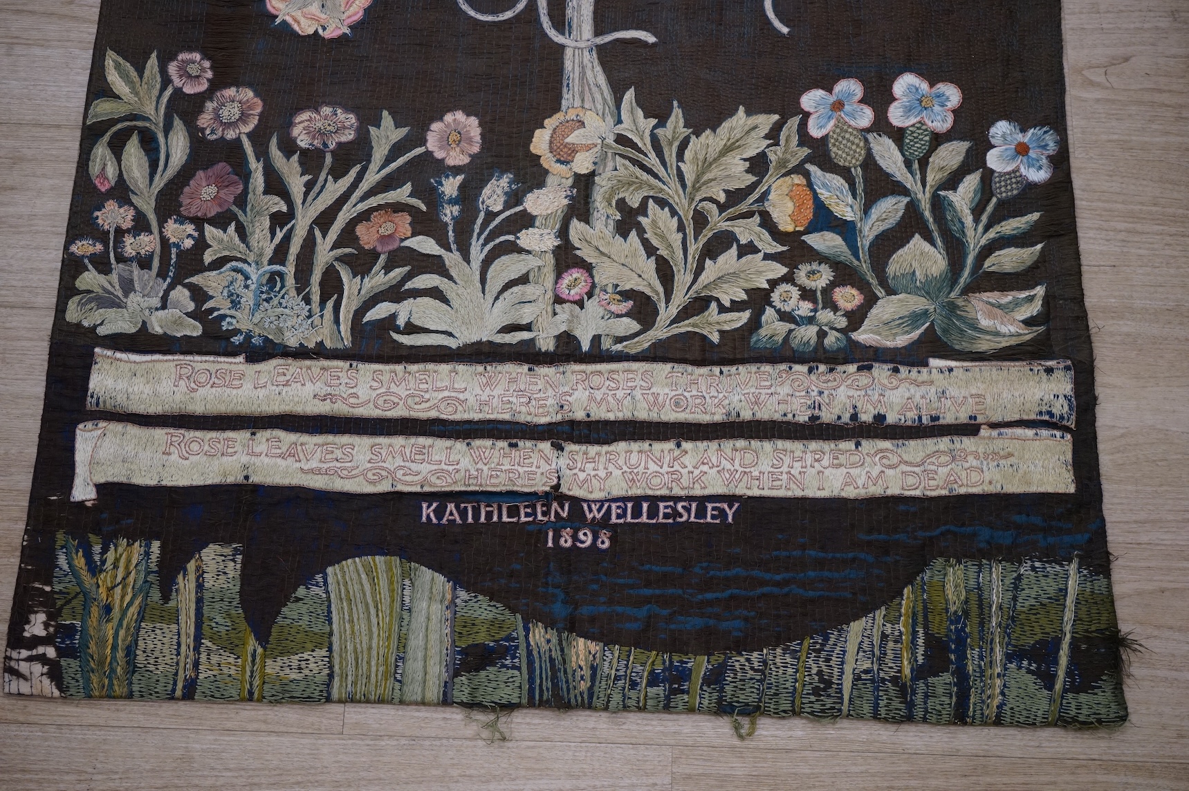 A large Arts and Crafts silk embroidered wall hanging, embroidered in the manner of May Morris with a large central scrolling flowering rose tree and banner embroidered with Salve and a two row motto below;, Rose leaves